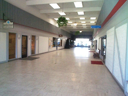 picture of Alpine Plaza before the remodeling - grey vinyl floor, grey and white walls, one bench in hallway
