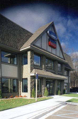 picture of Gaylord Ford Dealership front entrance - building is in the Alpine theme and constructed of dark tan decorative concrete masonry units, lighter tan trim, and architectural shingled roof