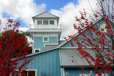 picture of Windjammer Marina in Alanson, Michigan - bright red foliage frames the marina's observation tower, which matches the building's light blue siding, white trim and grey metal roof
