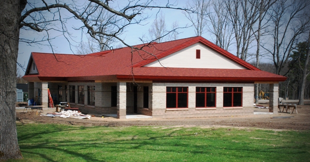 picture of exterior of dining hall under construction with red shingle roof and decorative concrete masonry unit walls