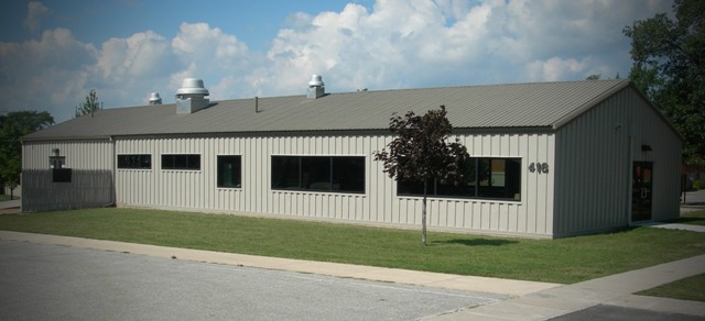 exterior picture of the CRTC Multi-Purpose Building 416 after improvements were made - the building has taupe metal siding with a darker shade of taupe in the metal roof, and tinted windows