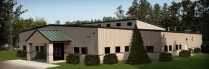 exterior picture of National Guard Armory building at Alpena Combat Readiness Training Center in Alpena, Michigan - tan metal siding and masonry construction with green metal roof