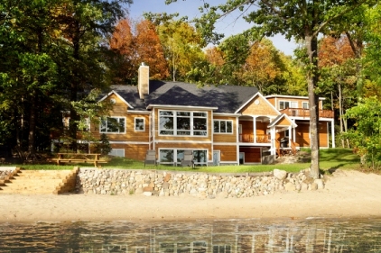 exterior photo of custom home on Dixon Lake with cedar siding and white trim, dark grey architectural shingle roof and custom windows - this sunny autumn afternoon photo was taken from out on the water on Dixon Lake