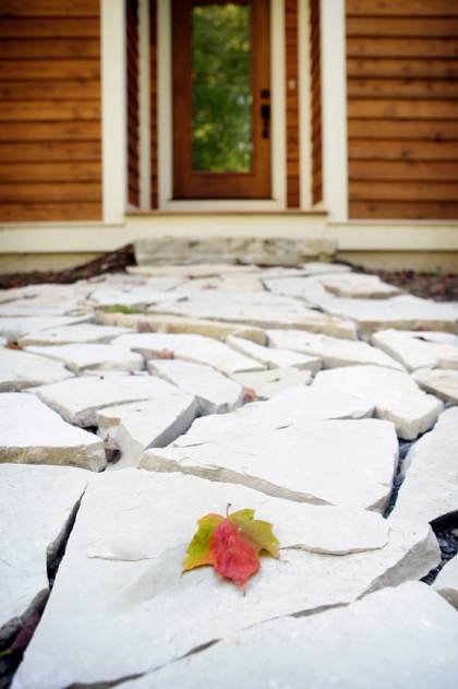 this photo is of the walkway to the road-side front entry of the home - a perfect autumn leaf has fallen onto the white stone walkway