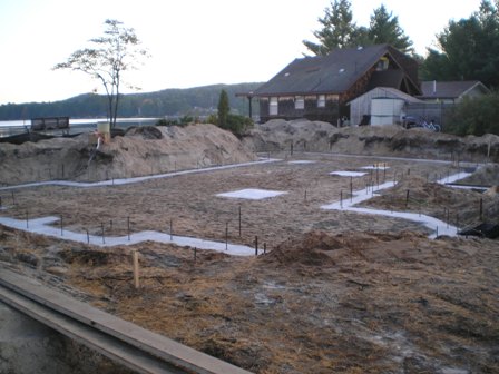 picture of the site of a new home under construction on Otsego Lake - the outline of the home can be seen by the footings that have been poured, and the lake is visible in the background