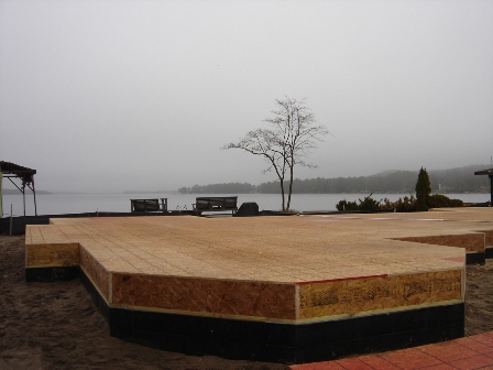 picture of floor framing construction for custom home being built on Otsego Lake - this photo looks toward the lake over the floor framing which shows the unique footprint of the home