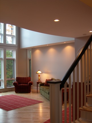 picture of waterfront home on Twin Lakes in Cheboygan, Michigan - this interior photo was taken from the front entry, looking into the living room facing the lake - recessed lighting supplements the abundant natural light coming in through the custom windows