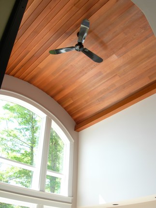 picture of waterfront home on Twin Lakes in Cheboygan, Michigan - this interior photo was taken in the living room, looking up at the curved wood plank ceiling which carries the curvature from the upper window construction through the room - the rich wood tones in the ceiling contrast with the soft ice wall color