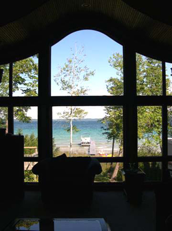 picture of custom lakefront cottage on West Bay, Traverse City, MI - this interior photo was taken from inside the home's living room, with lights intentionally low to maximize the impact of the view of Traverse Bay - the custom windows form a beautiful frame for the spectacular view of the water