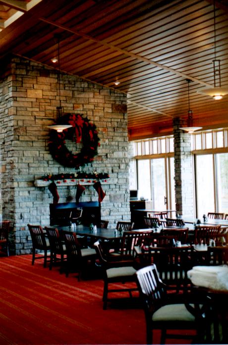 interior picture of UAW Black Lake Golf Course Clubhouse - main dining room with stone fireplace, wood plank ceilings, natural light supplemented by pendent and recessed light fixtures